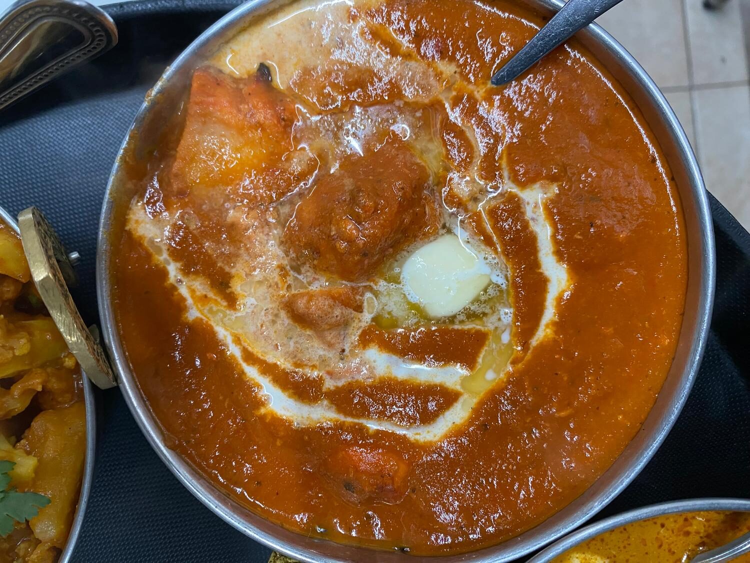 Butter chicken in a copper karahi with a swirl of cream and pat of butter
