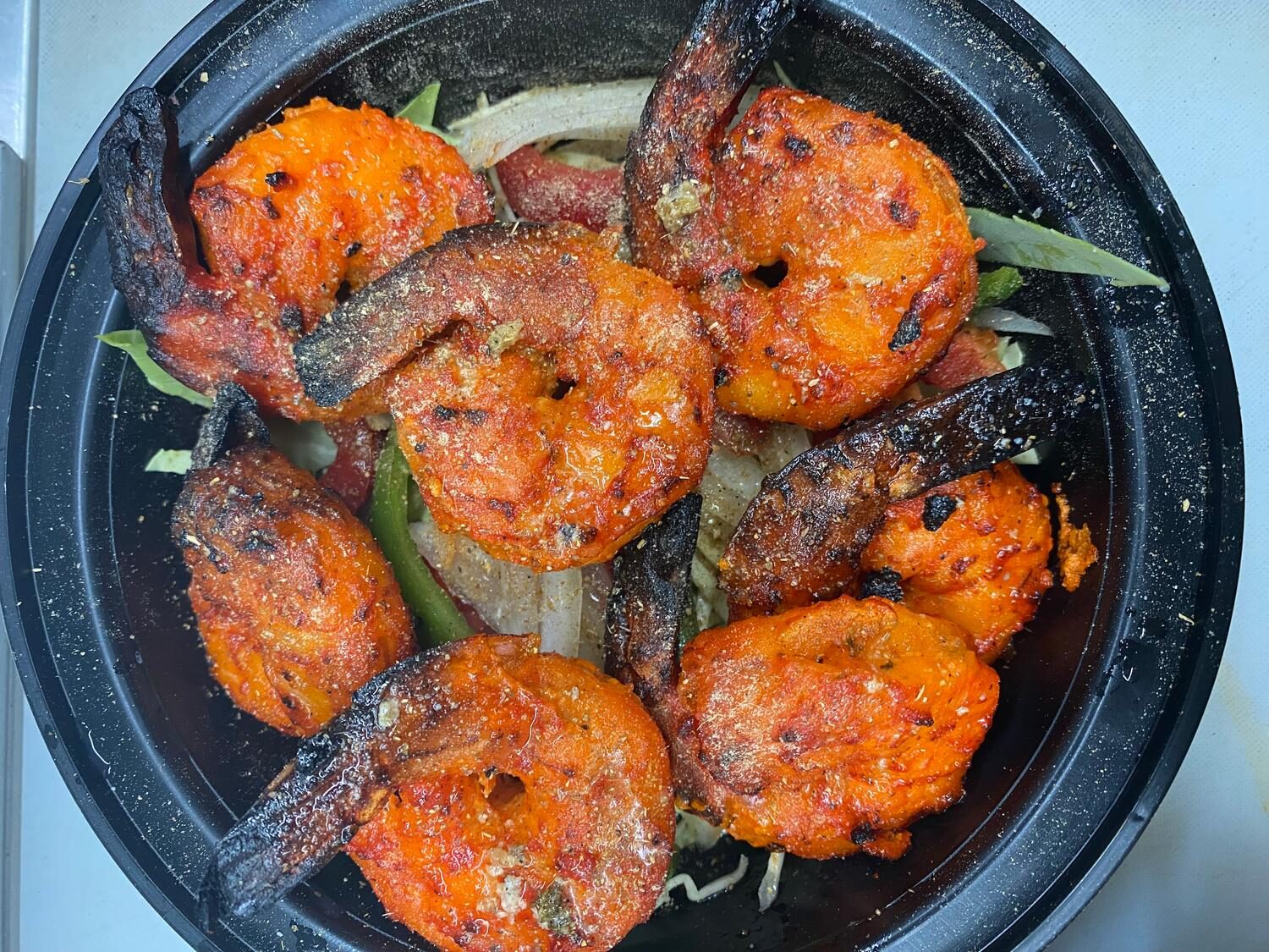 Tandoori shrimp with charred spice crust served over onions and peppers